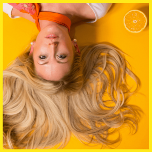 10 Online Fashion Stylists Almost Haute-Couture - girl lying down with blond hair on a yellow background