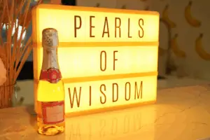 Champagne bottle displayed beside a “Pearl of Wisdom” sign in a styled New Year setting